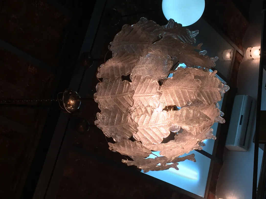 Two antique hanging lamps with decorative shapes hanging from a dark ceiling.