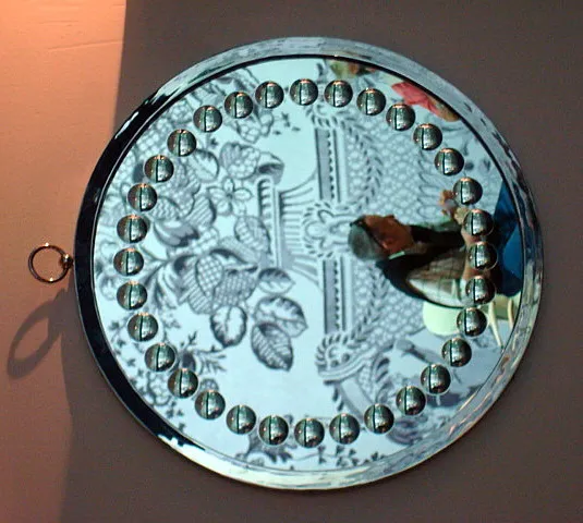 miroir rond antique avec biseaux décoratifs, présente des détails clairs sur sa surface.