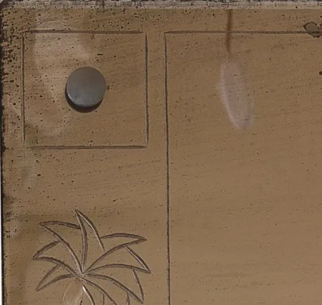 Miroir ancien avec un design floral gravé, fond neutre.