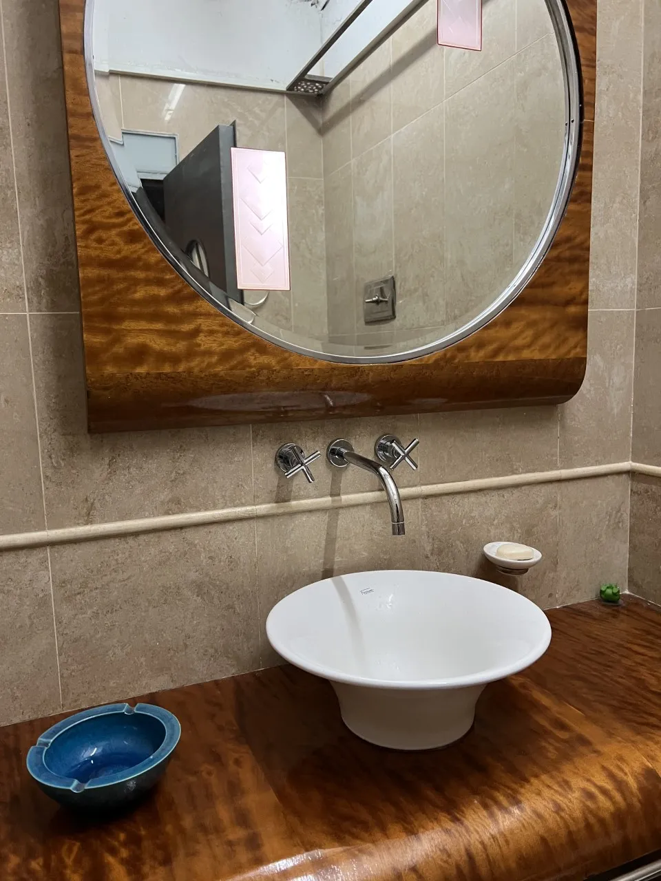 Espejo antiguo redondo sobre un lavabo blanco con ambiente cálido