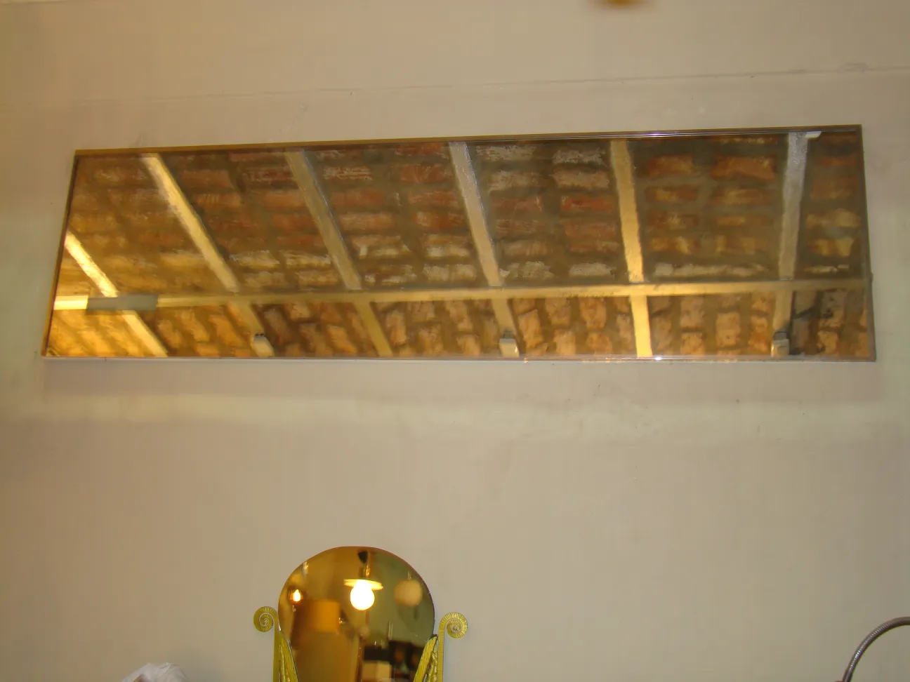 Antique wall mirror with a golden frame reflecting the ceiling.