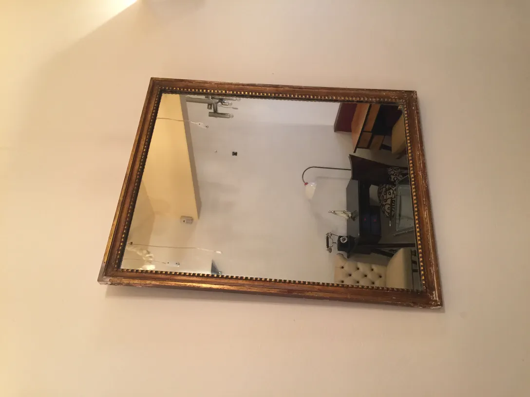 Miroir ancien avec cadre décoratif accroché au mur.