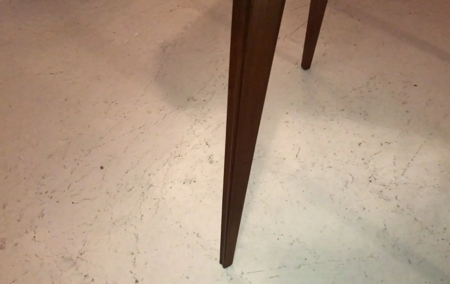 Antiker Tisch für vier Personen mit eleganten Füßen, schlichte Umgebung.