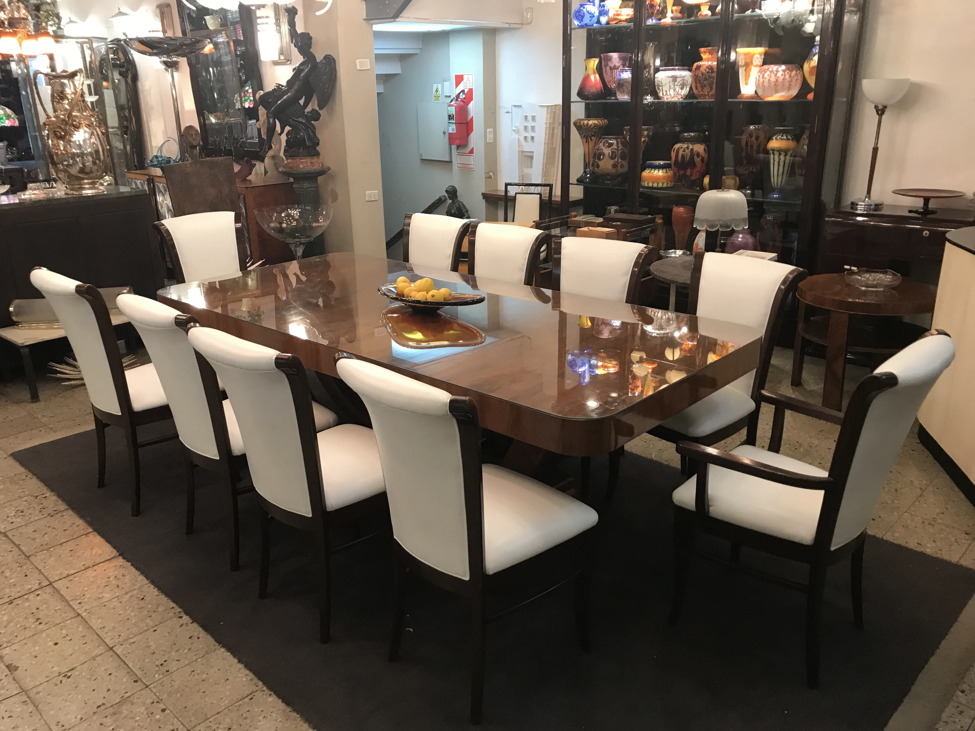 Antique dining table for 10 people with white chairs.