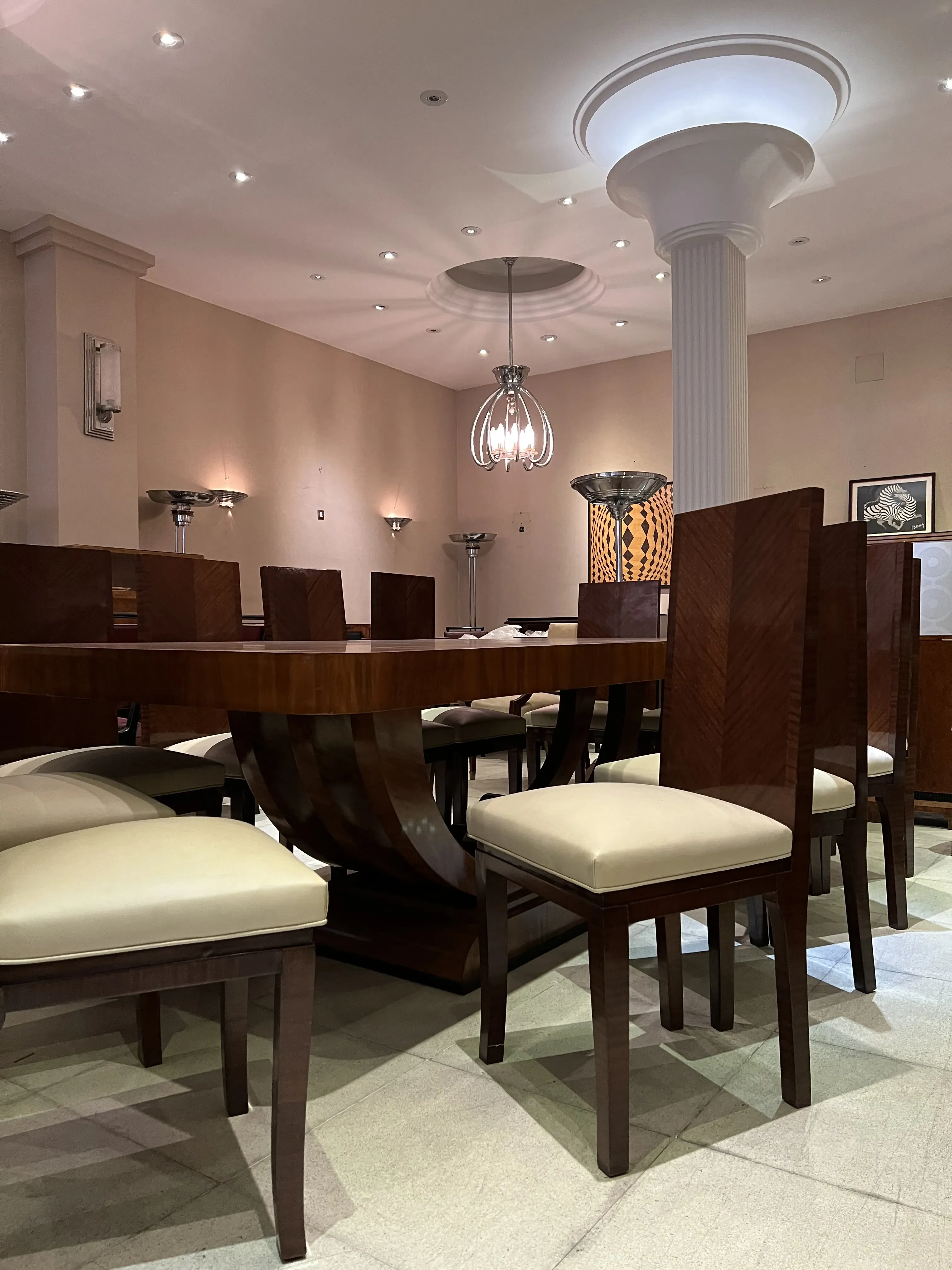 Mesa de comedor antigua de estilo Art Deco para 10 personas, decorada con sillas elegantes y un ambiente luminoso.