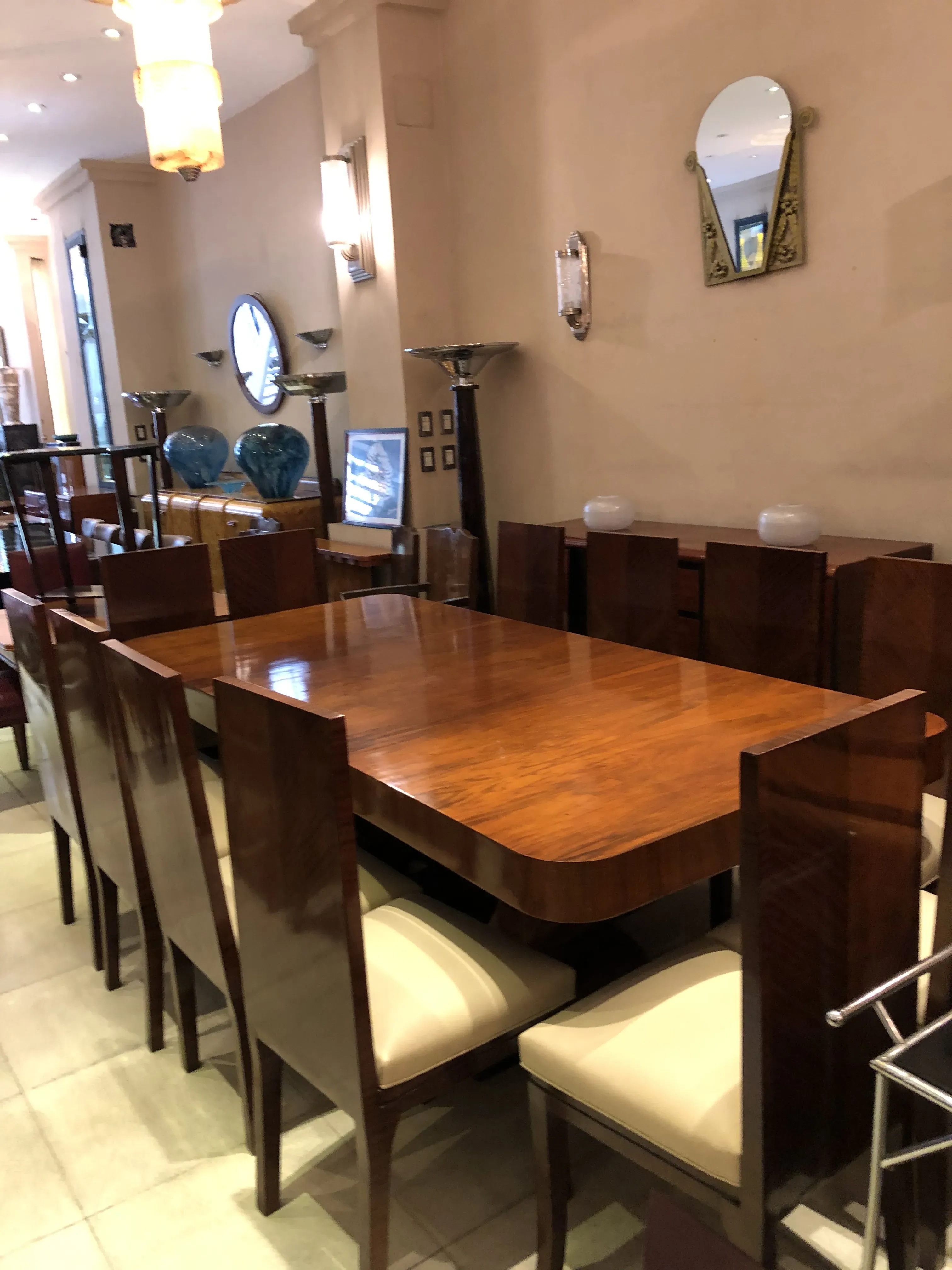 Table à manger ancienne de style Art Deco pour dix personnes, entourée de chaises. Atmosphère conviviale.