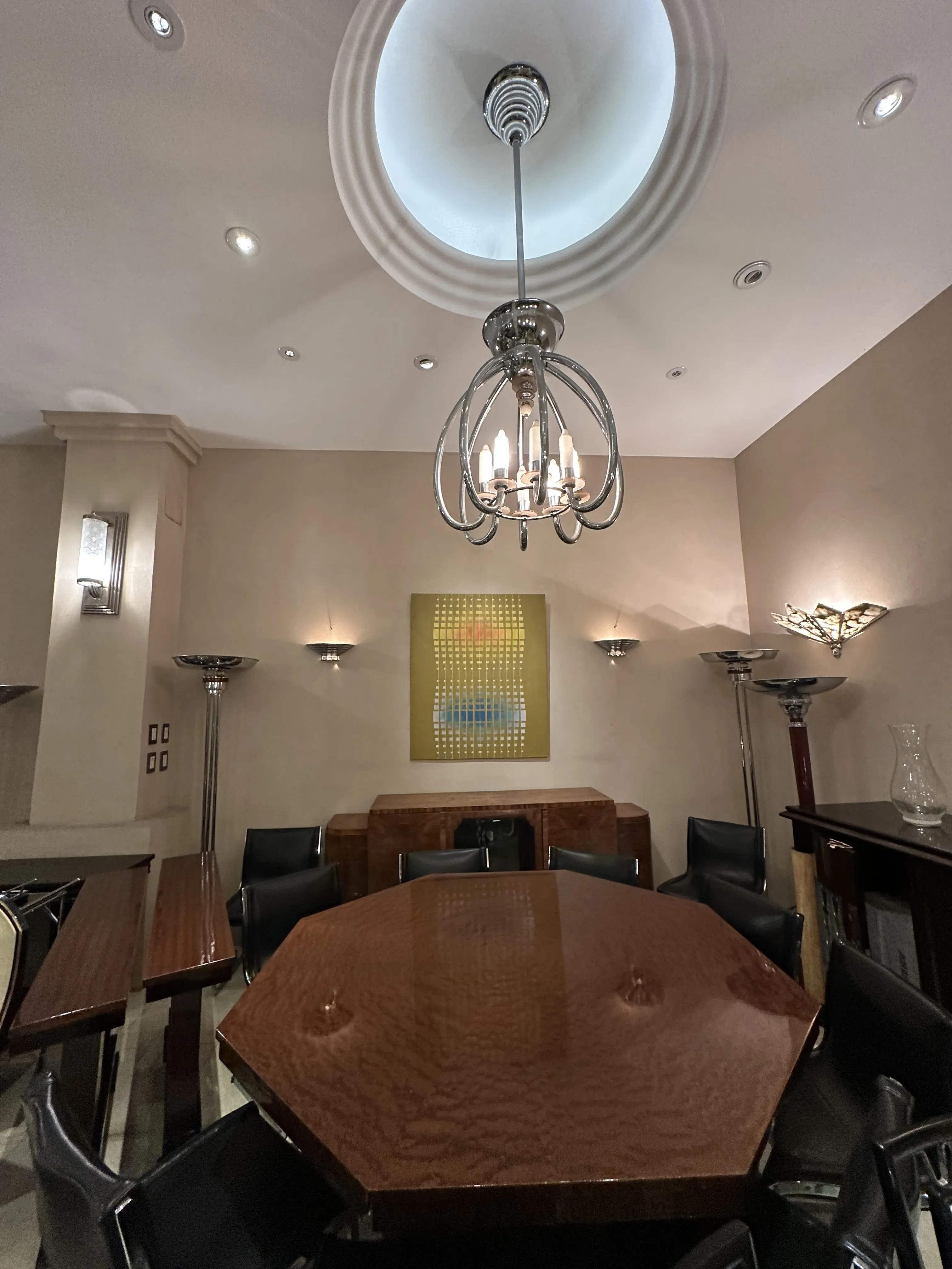 Mesa de jantar octogonal antiga para oito pessoas, com cadeiras pretas e um ambiente elegante.