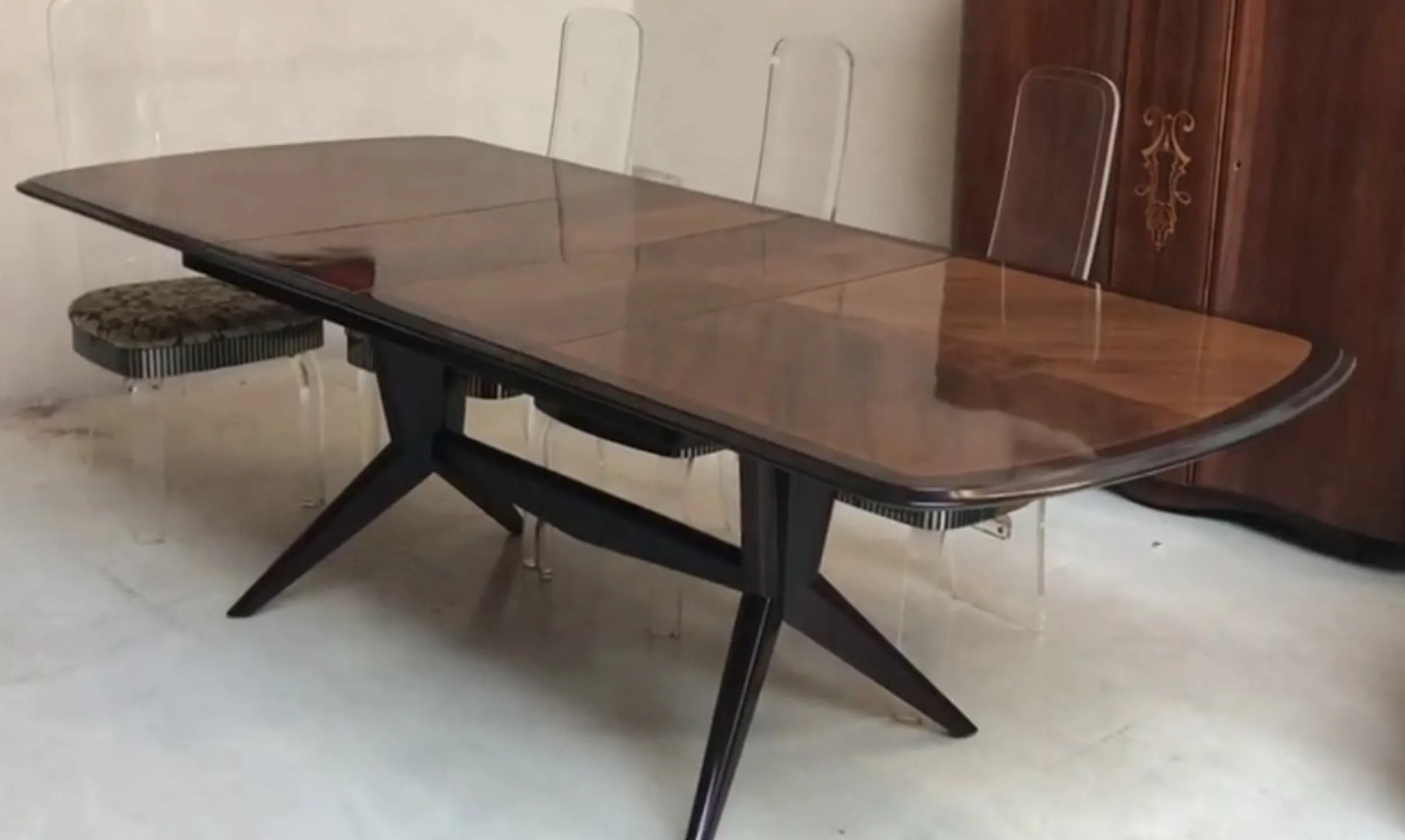Mesa de comedor antigua para ocho personas con sillas transparentes.