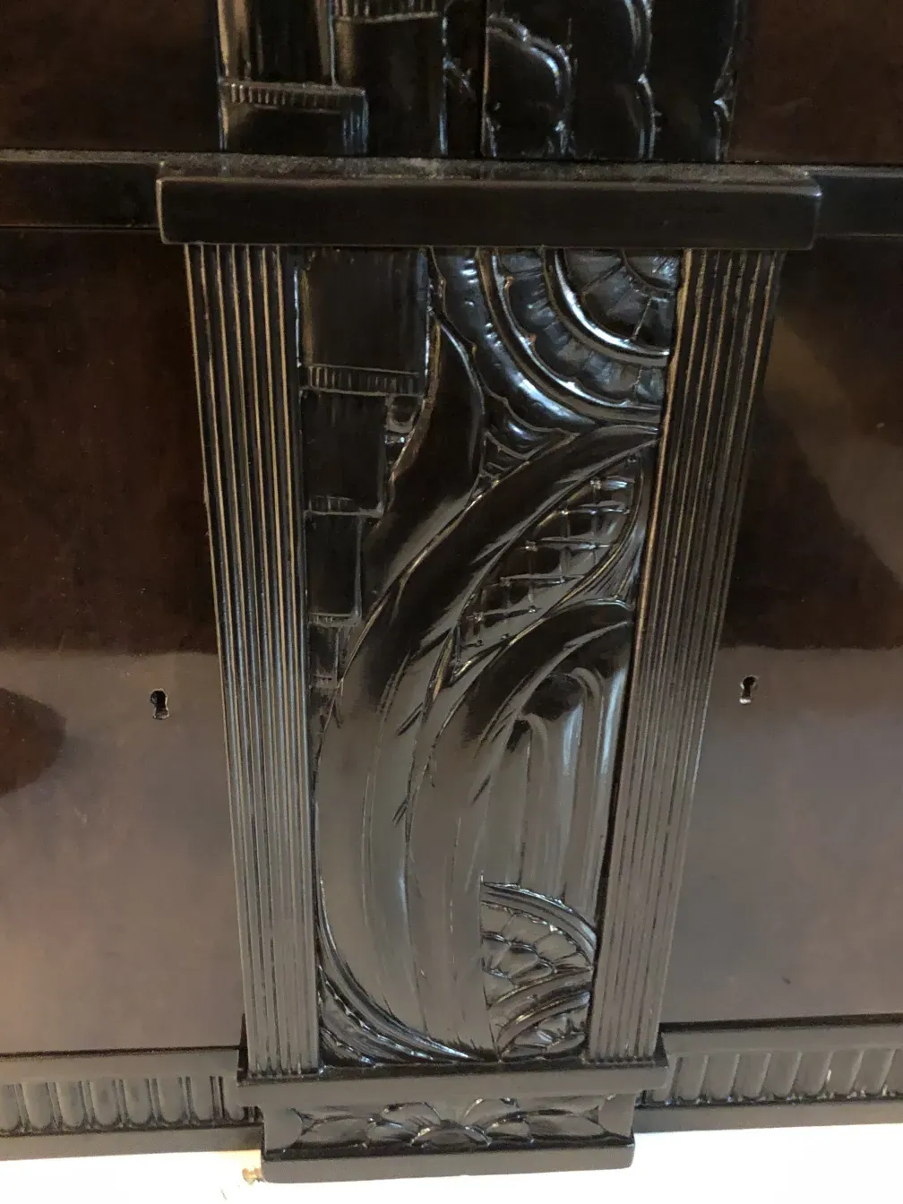 Détail d'une bibliothèque ancienne avec des motifs sculptés à la main et une finition brillante, dans un cadre classique.