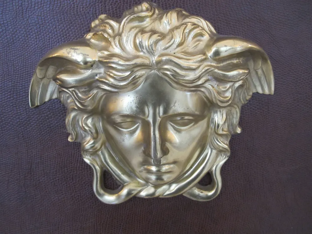 Tête décorative en relief avec des détails stylisés, faisant partie d'une bibliothèque antique