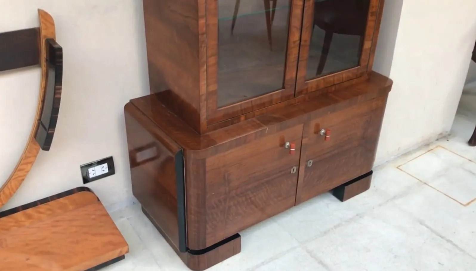 Antikes Bücherregal mit Glastüren und unterer Ablage, in einer modernen Umgebung.