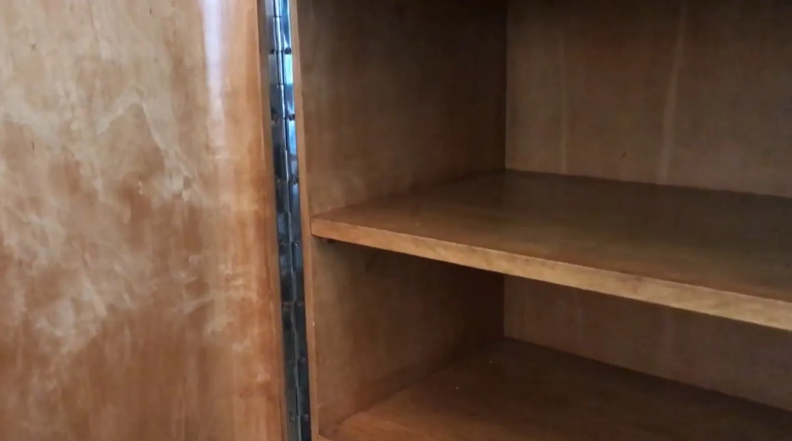 Antikes Bücherregal mit leeren Regalen in einer einfachen Umgebung.