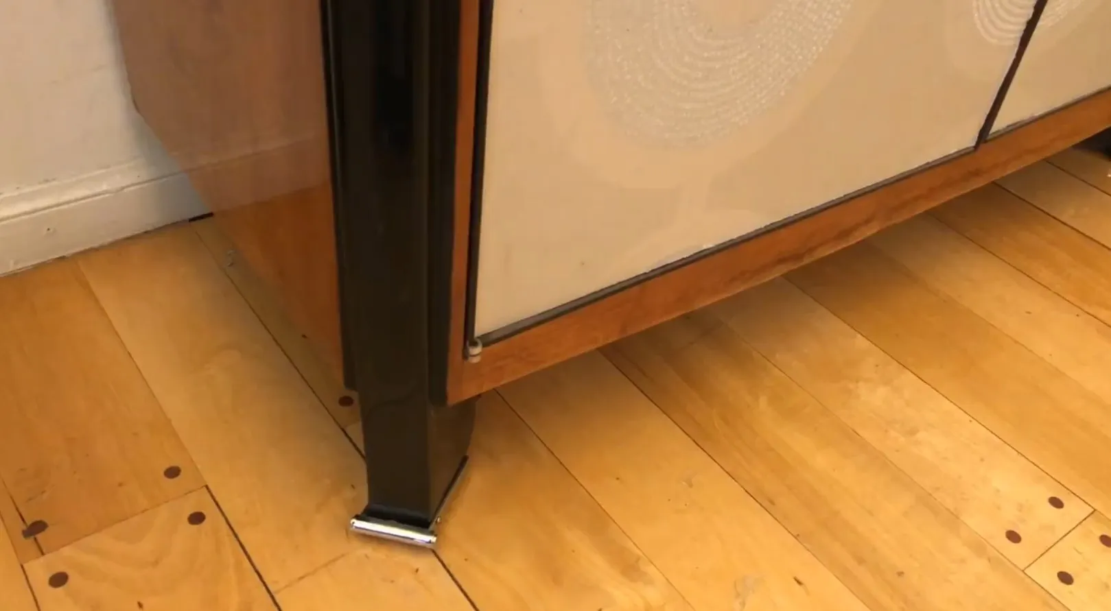 Detail eines alten Bücherregals mit leeren Regalen und elegantem Fuß