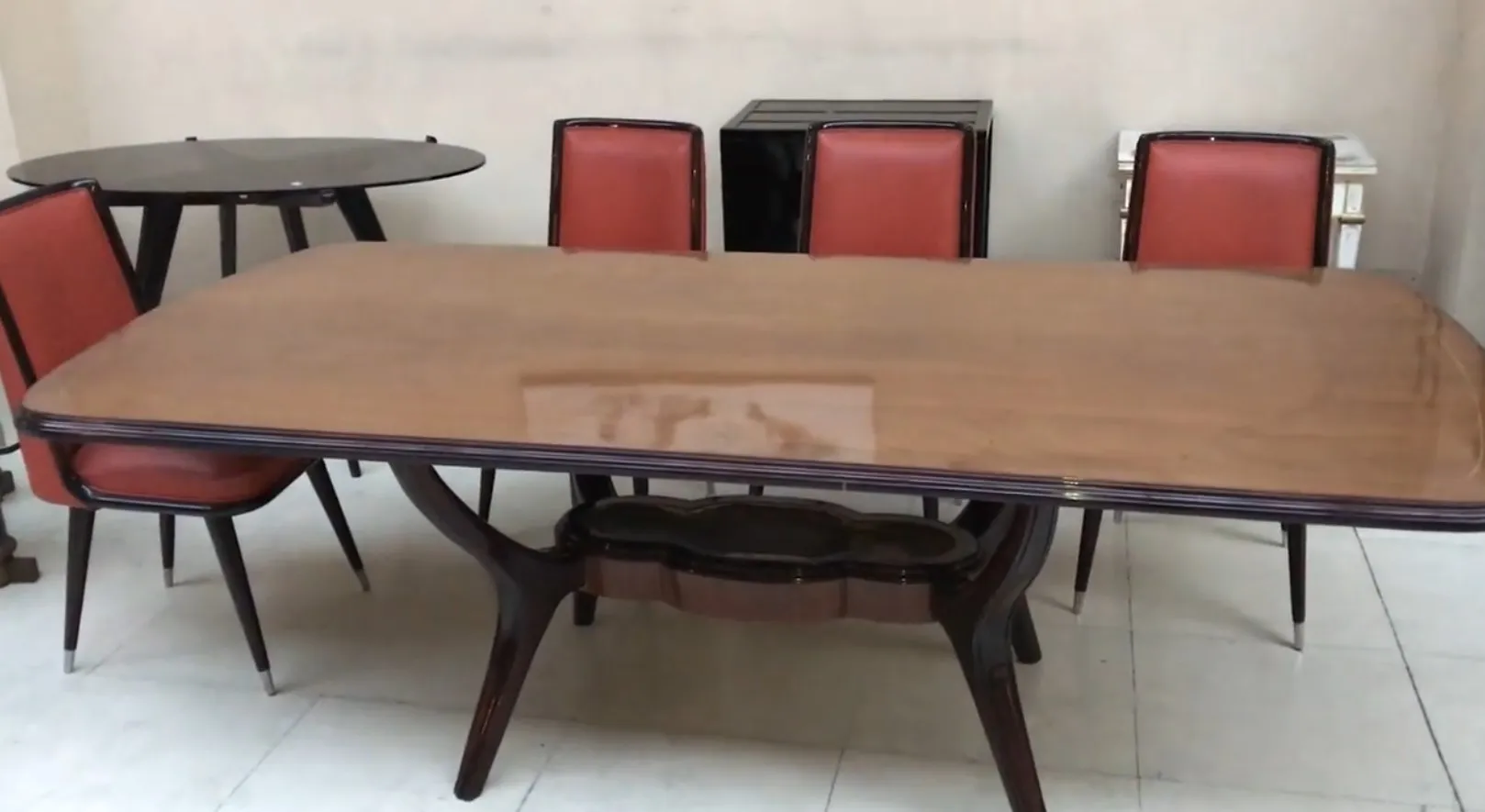 Mesa de comedor antigua de madera con sillas rojas en un ambiente neutro.