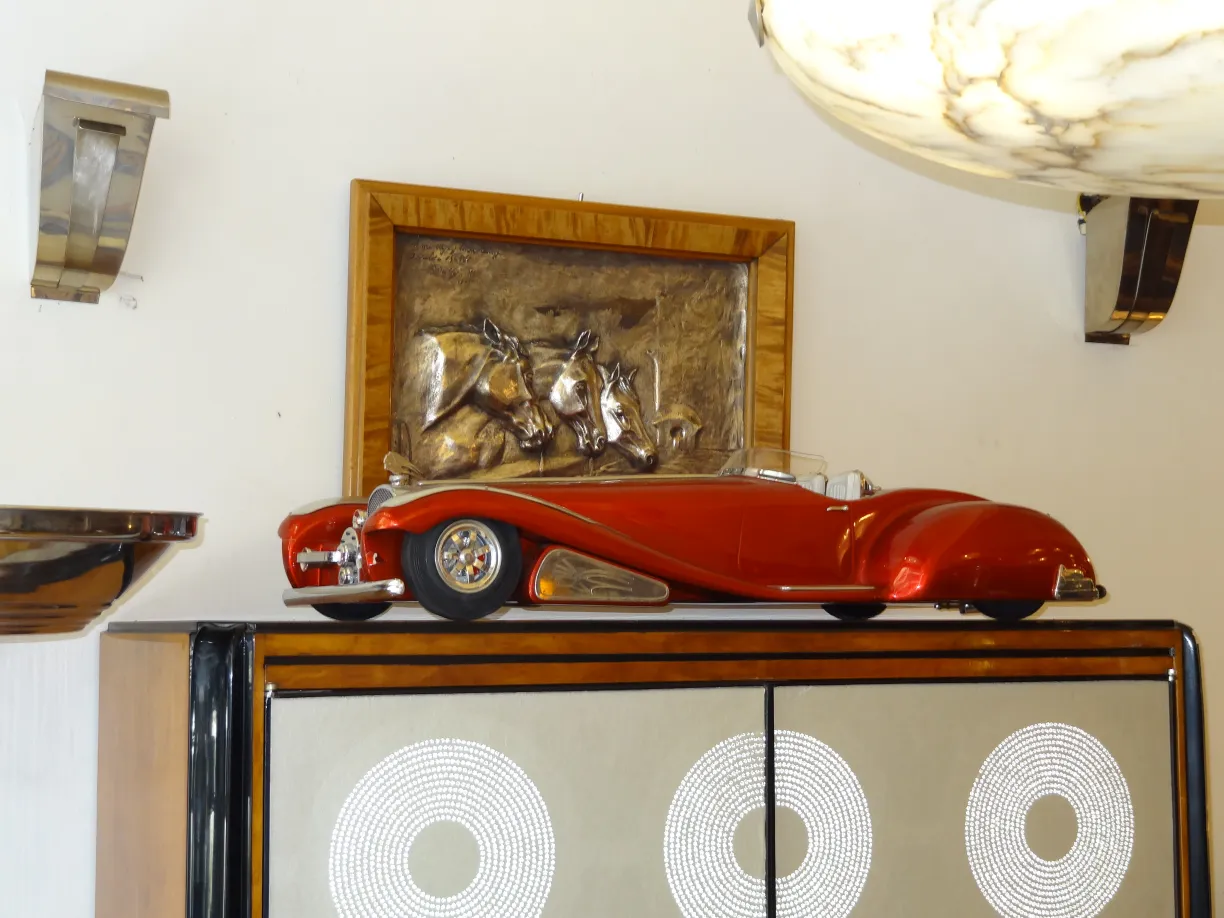 Antique bookcase with a red toy car and wall art.