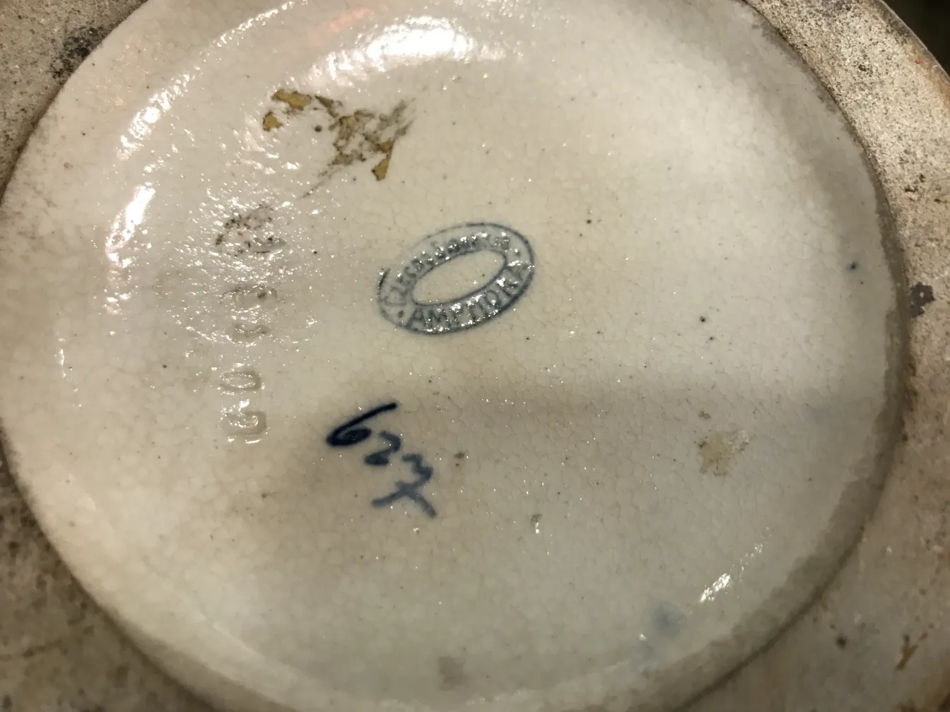 Vista della base di una antica ceramica con segni, tonalità chiare e dettagli visibili.