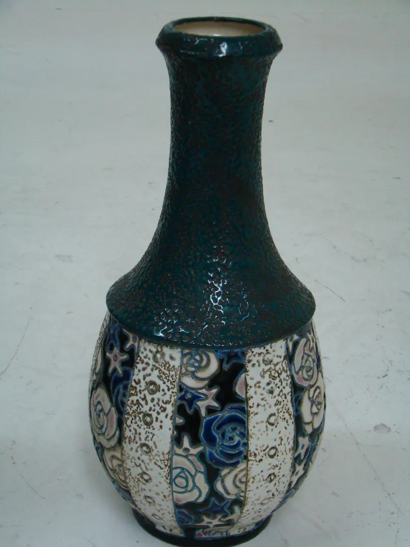 Antigua cerámica con detalles en azul y blanco, con una forma elegante. Ambiente sencillo.