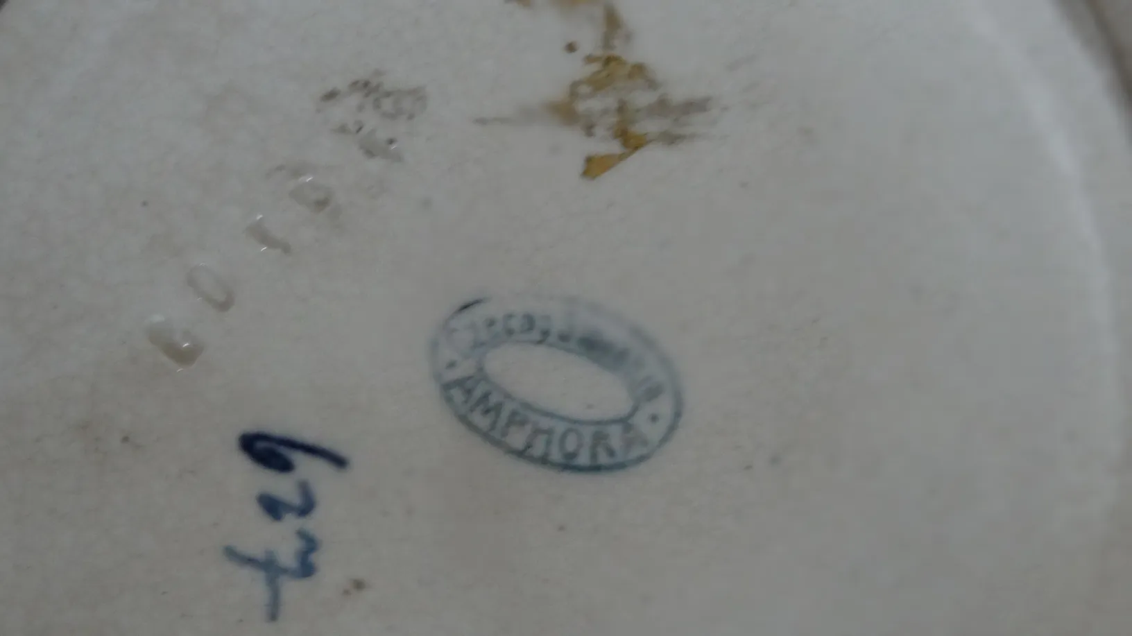 Vista inferior de antiga cerâmica com selo visível, detalhes em cores claras.