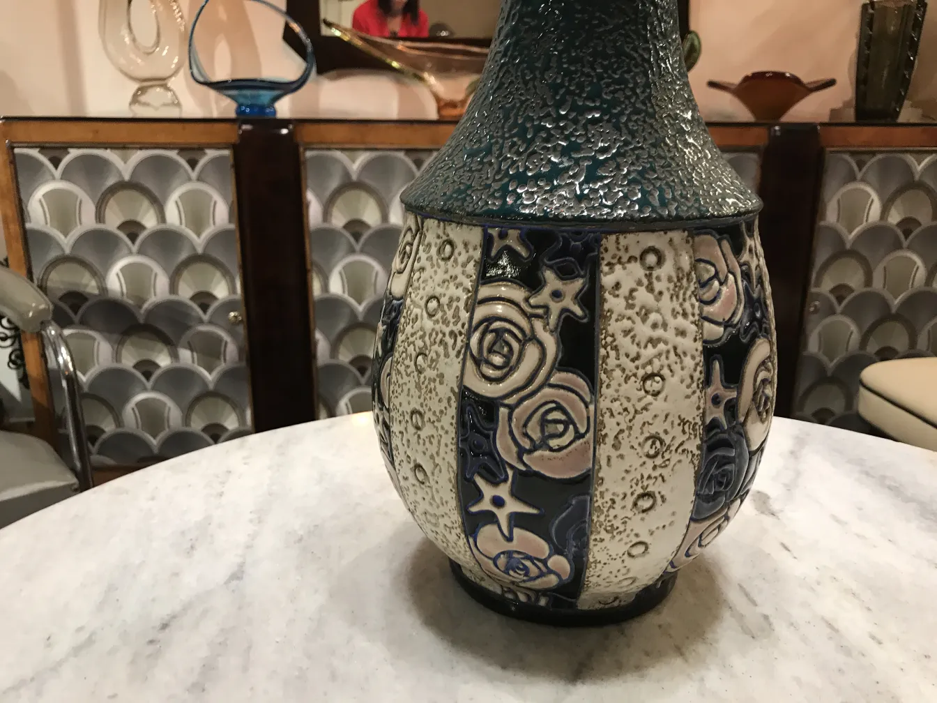 Amphore en céramique ancienne avec motifs floraux, dans un cadre décoratif.