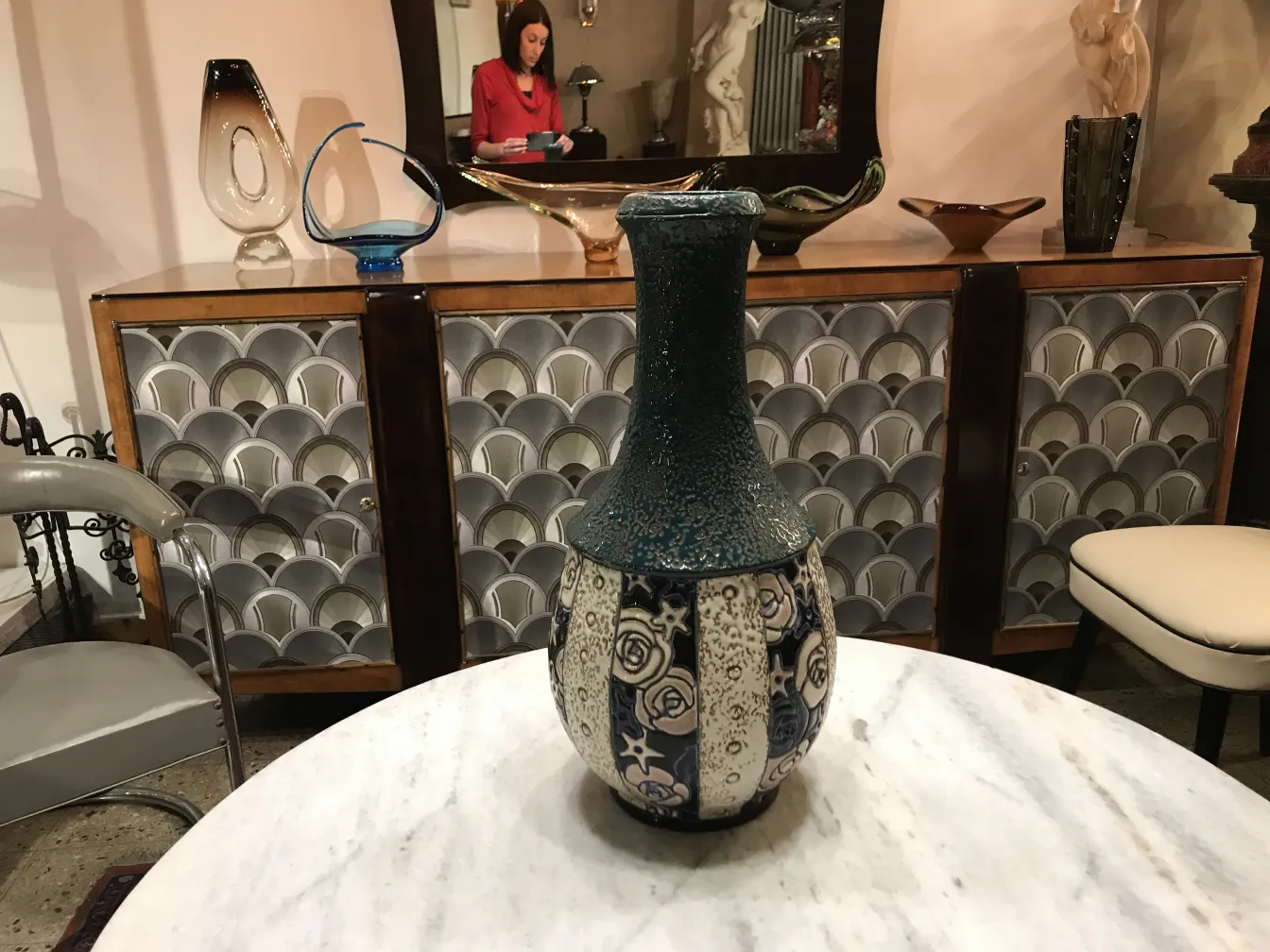 Vase ancien en céramique décorée en bleu et blanc, avec un motif floral sur un fond clair.