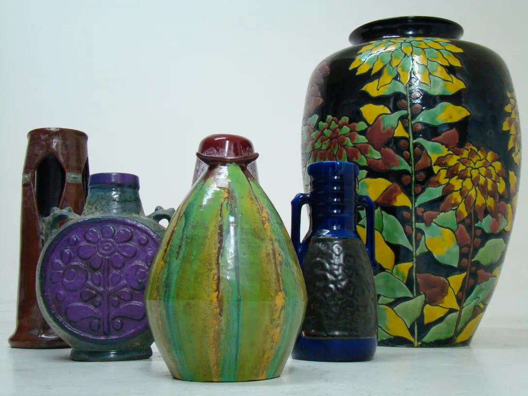 Vasos de cerámica antigua de varios colores y formas con detalles florales.