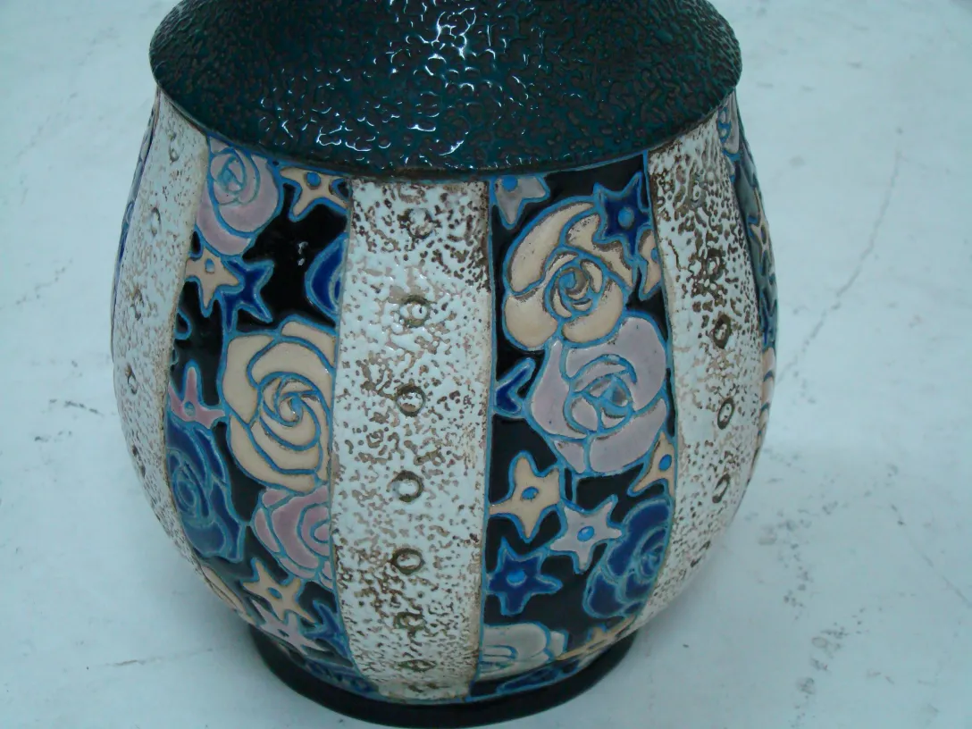 Amphore ancienne en céramique avec motif floral en tons de bleu et rose, fond clair.