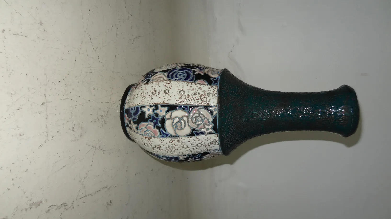 Antike Keramikvase mit Blumenmustern in dunklen und hellen Farben.