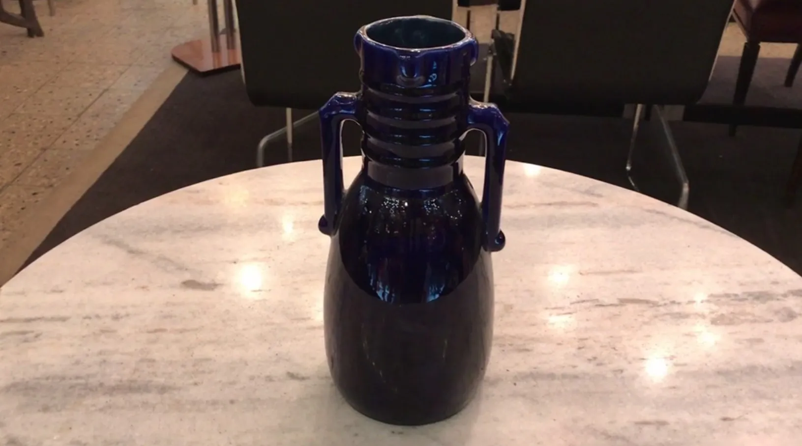 vase ancien en céramique bleue avec des détails décoratifs sur un fond en marbre