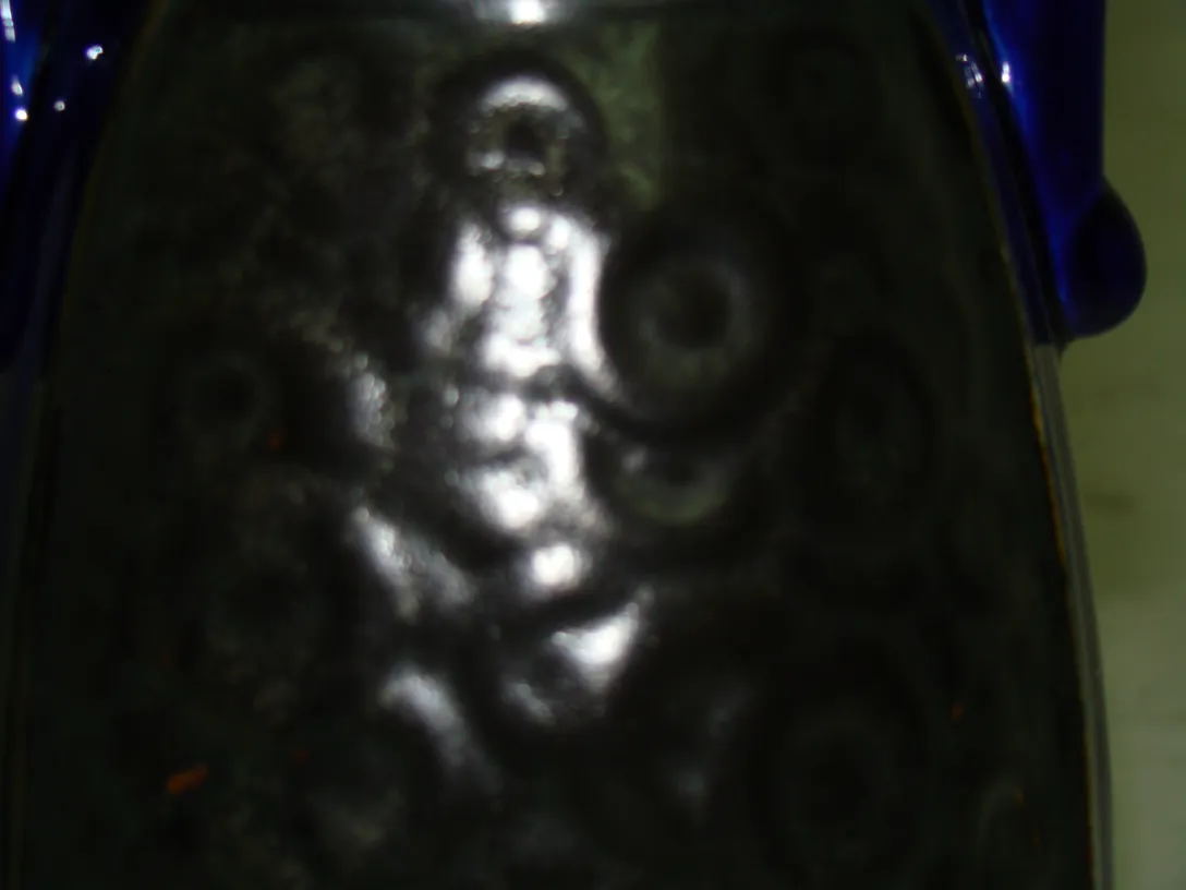 Céramique décorative antique avec motifs en relief et couleurs sombres.