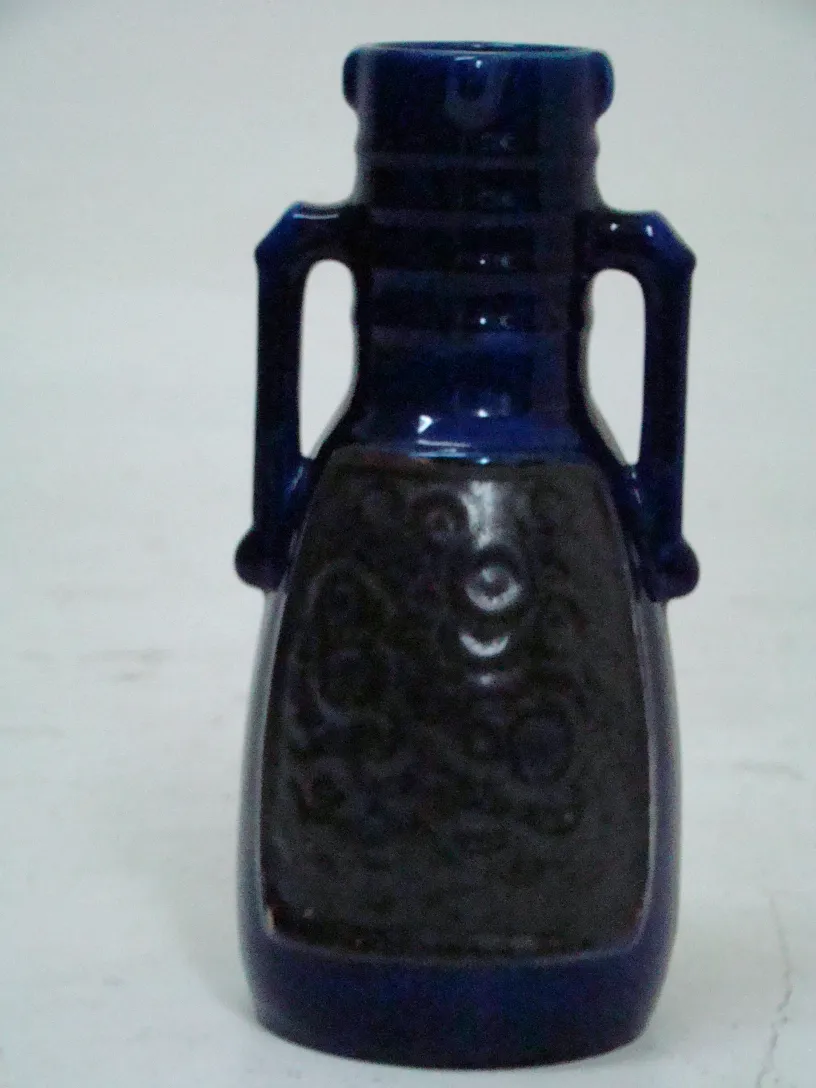 Una antigua cerámica decorativa con detalles en azul y negro, fondo neutro.