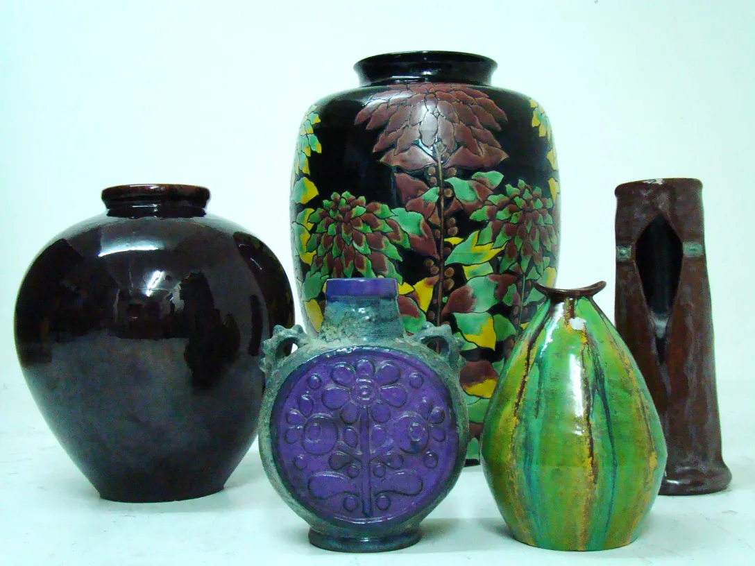 Varias piezas de cerámica antigua en diferentes formas y colores junto a un fondo neutro.