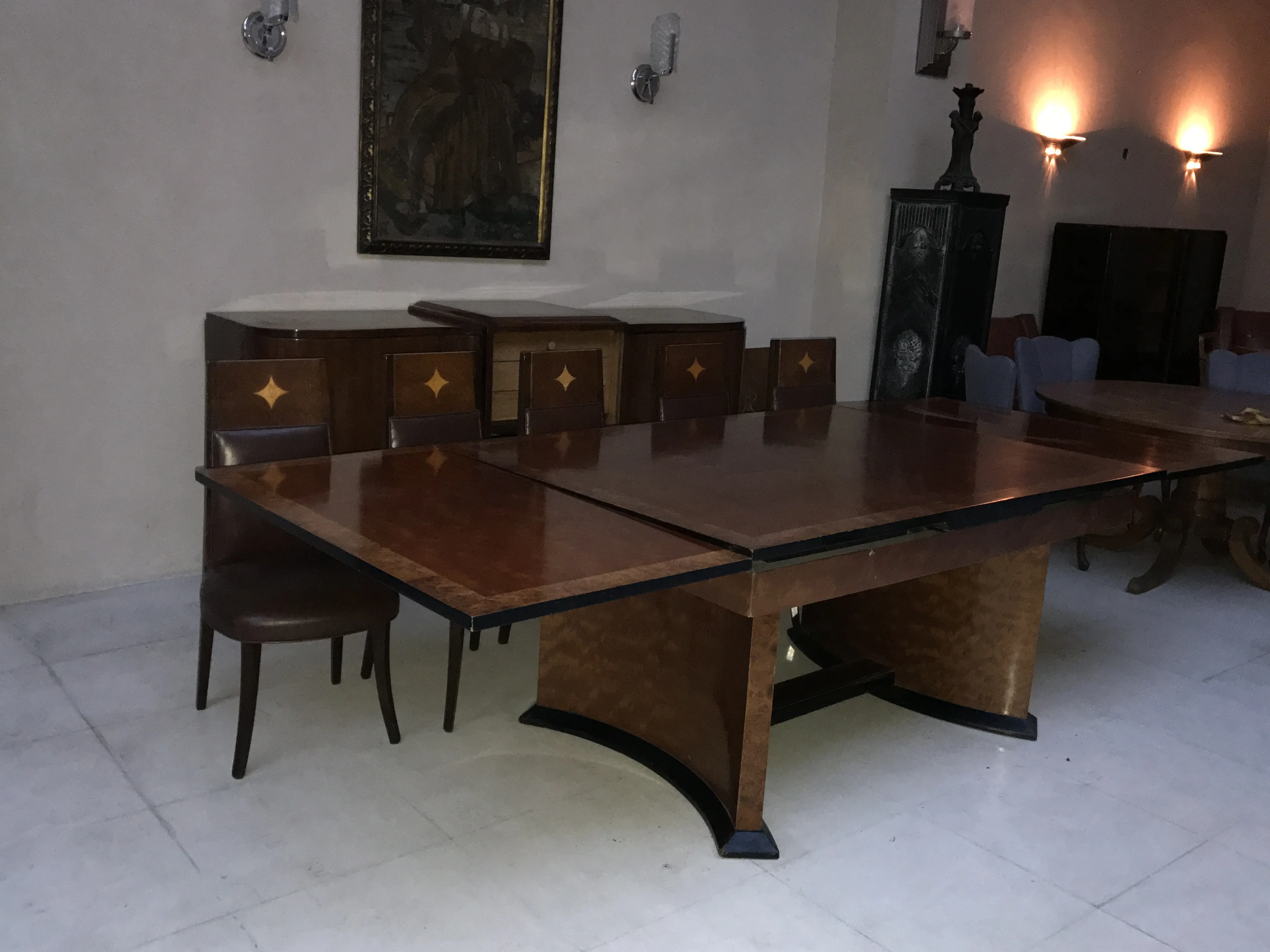 Antique dining table for 12 people, with leather chairs in a cozy setting.