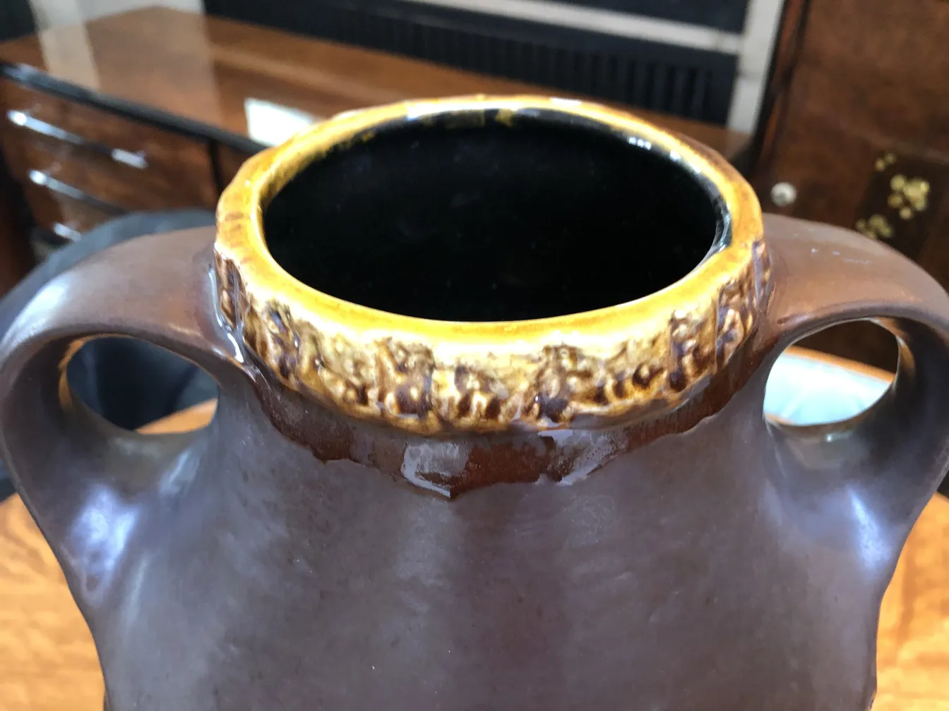 Antiga cerâmica com decoração na parte superior e alças