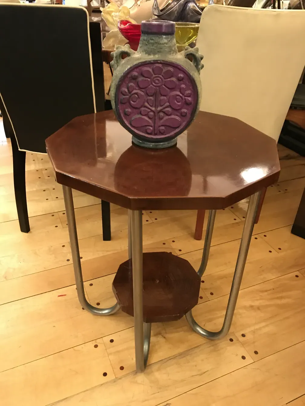 Jarrón cerámico antiguo en mesa octagonal, ambiente acogedor.