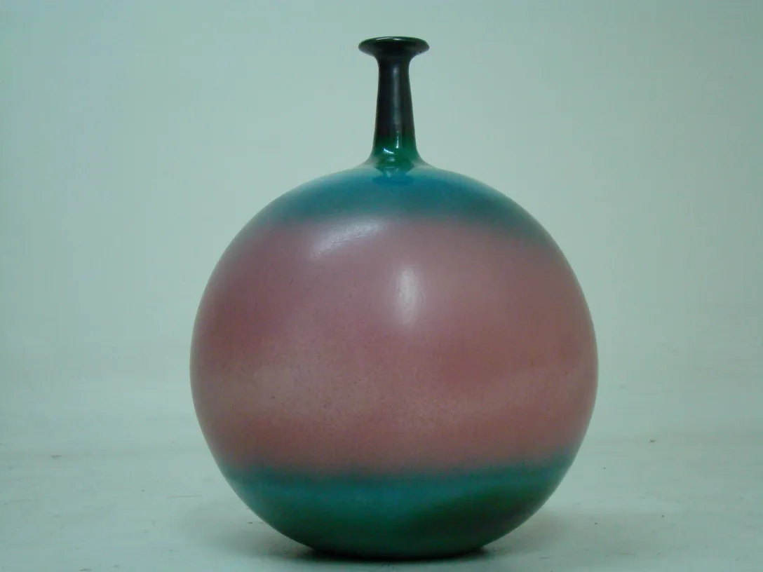 Ancienne céramique sphérique avec finition colorée en rose et vert.