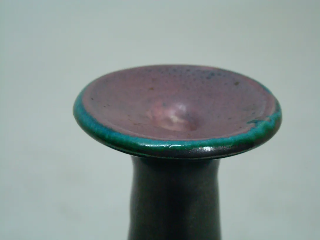 Copo de cerâmica antiga com borda verde e roxa.