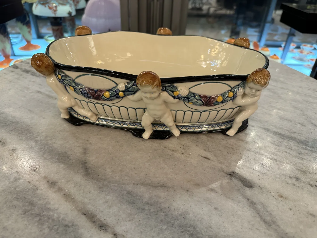 Antique ceramic with cherub figures on the sides.