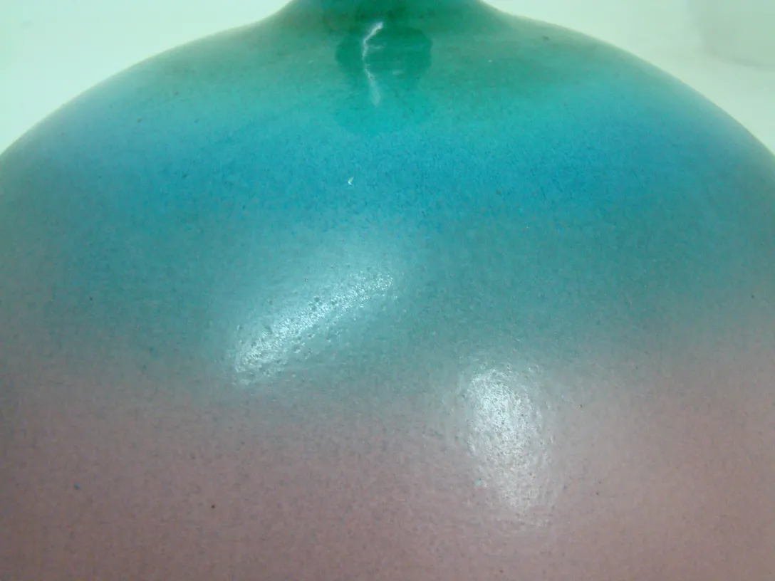 Antigua cerámica con un suave degradado de colores azul y rosa, forma esférica.