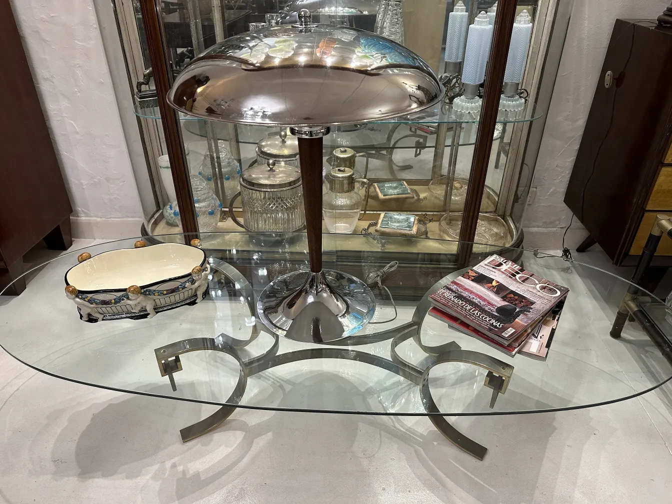 Vassoio di ceramica antico con dettagli colorati, esposto su un tavolo di vetro con lampada.