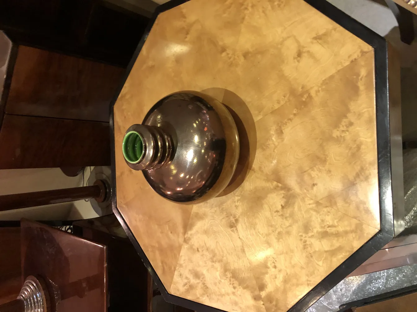 antique ceramic with round design and green neck, decorating an octagonal table