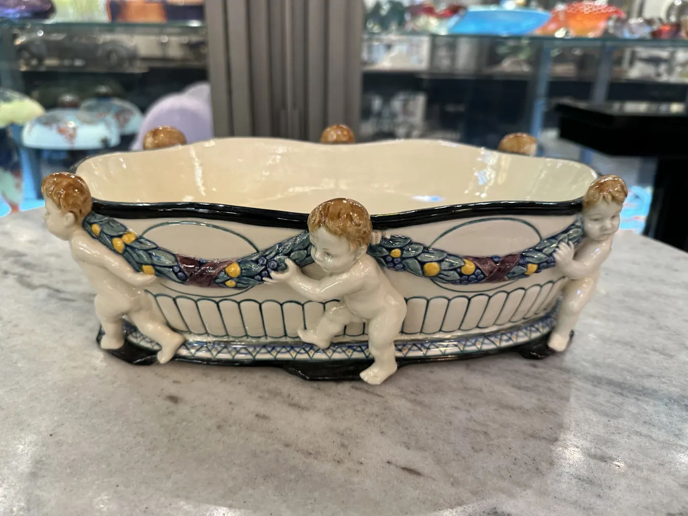 Antique ceramic featuring cherubs and floral patterns.