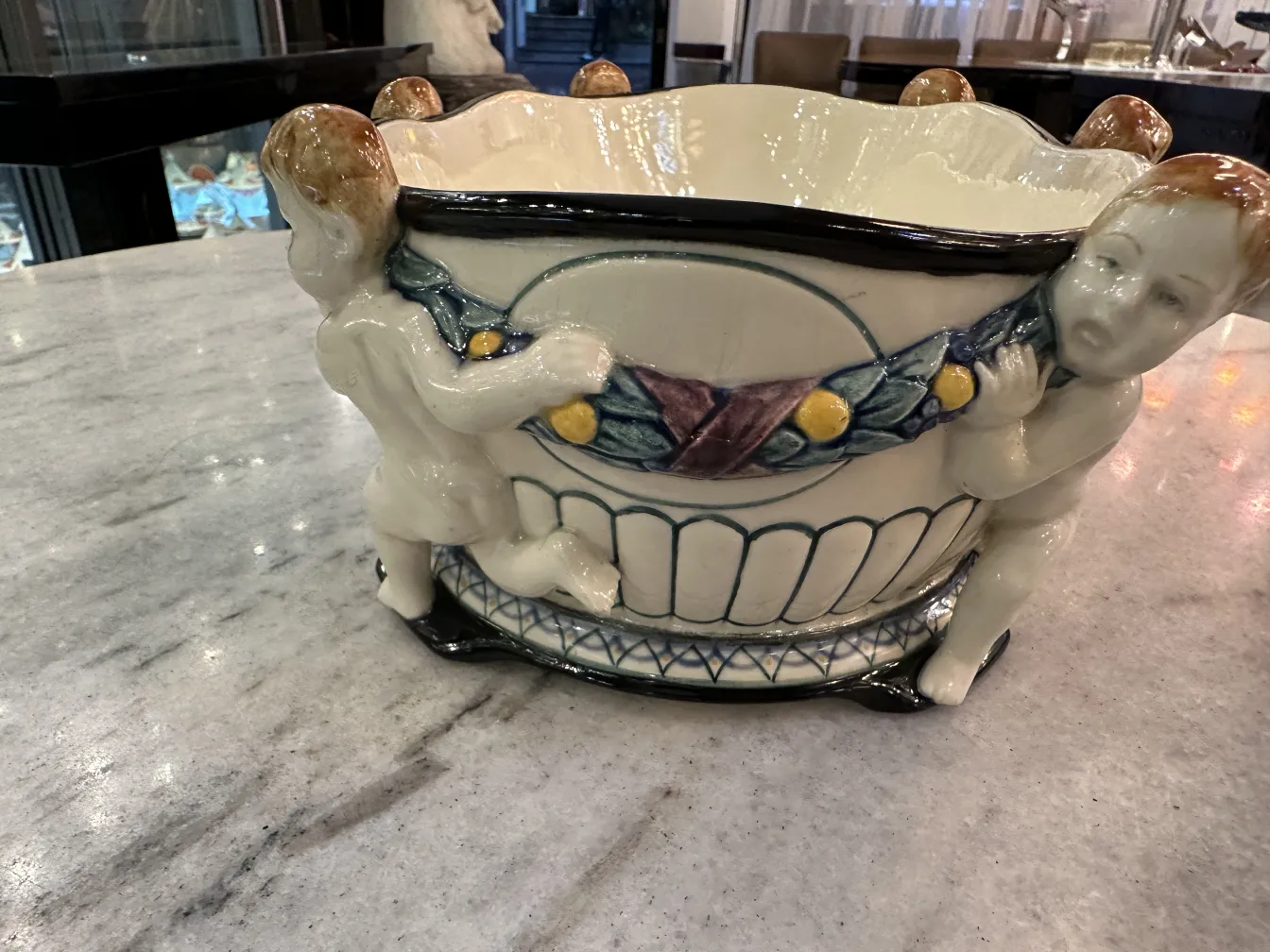 Ceramica decorativa antica con figure allegoriche alla base.