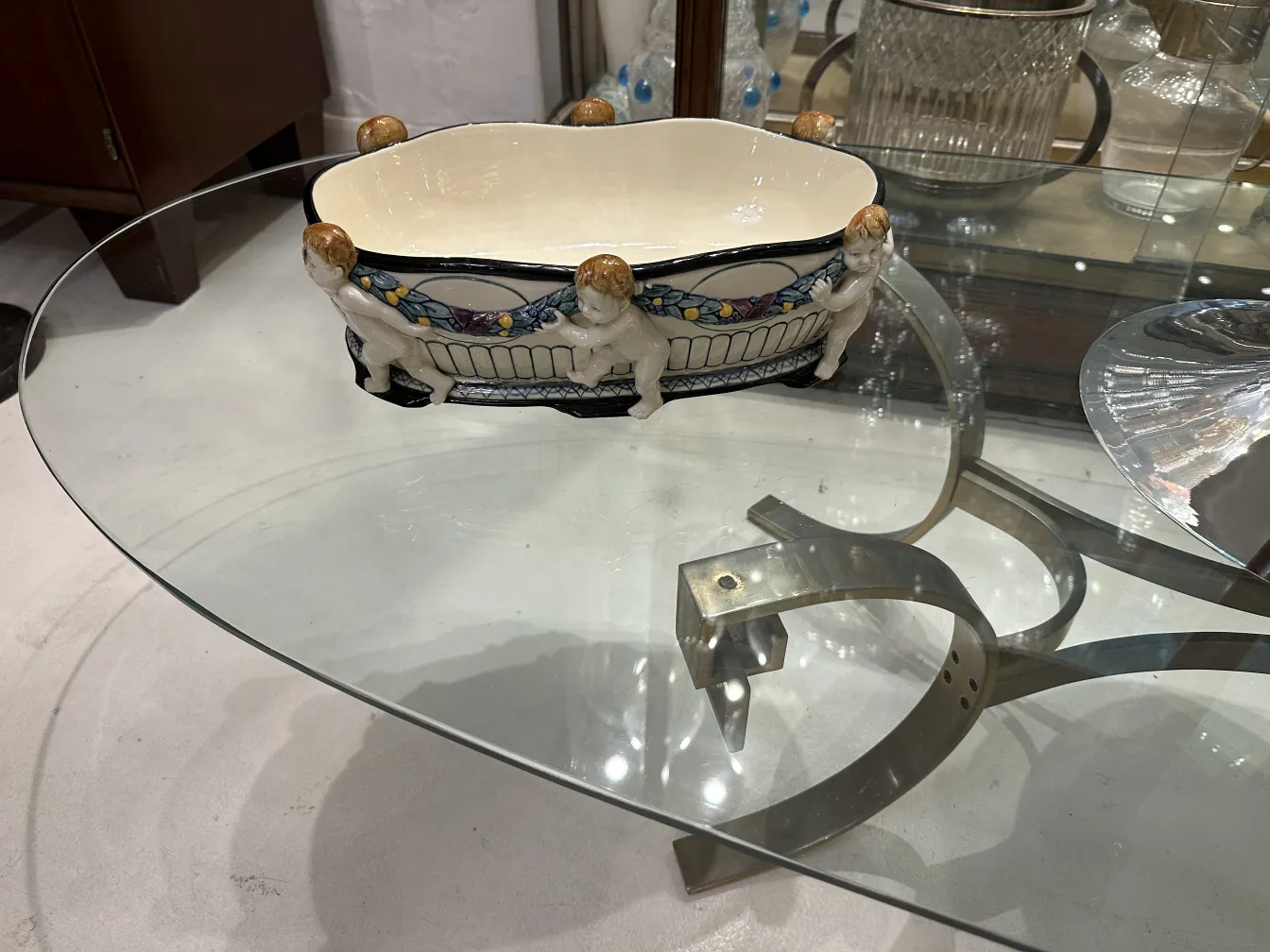 Antike Keramik mit Figuren und lebendigen Farben auf einem Glastisch präsentiert.