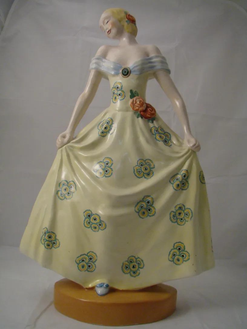 Figura decorativa de cerámica con vestido amarillo y flores