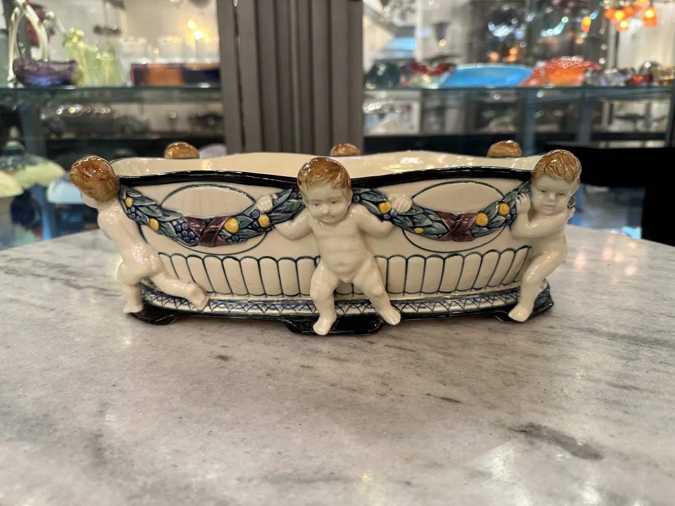 Antike Keramik mit Figuren von Kindern, die einen Kranz halten.