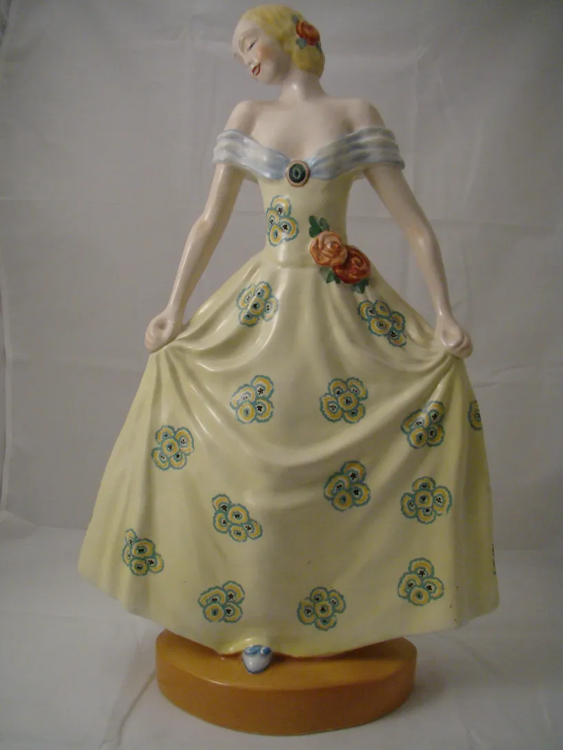 Una antigua figura de cerámica de dama, con vestido amarillo decorado con flores