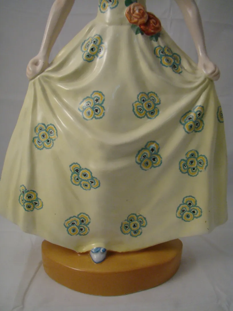 Figura antiga de cerâmica com vestido amarelo e flores