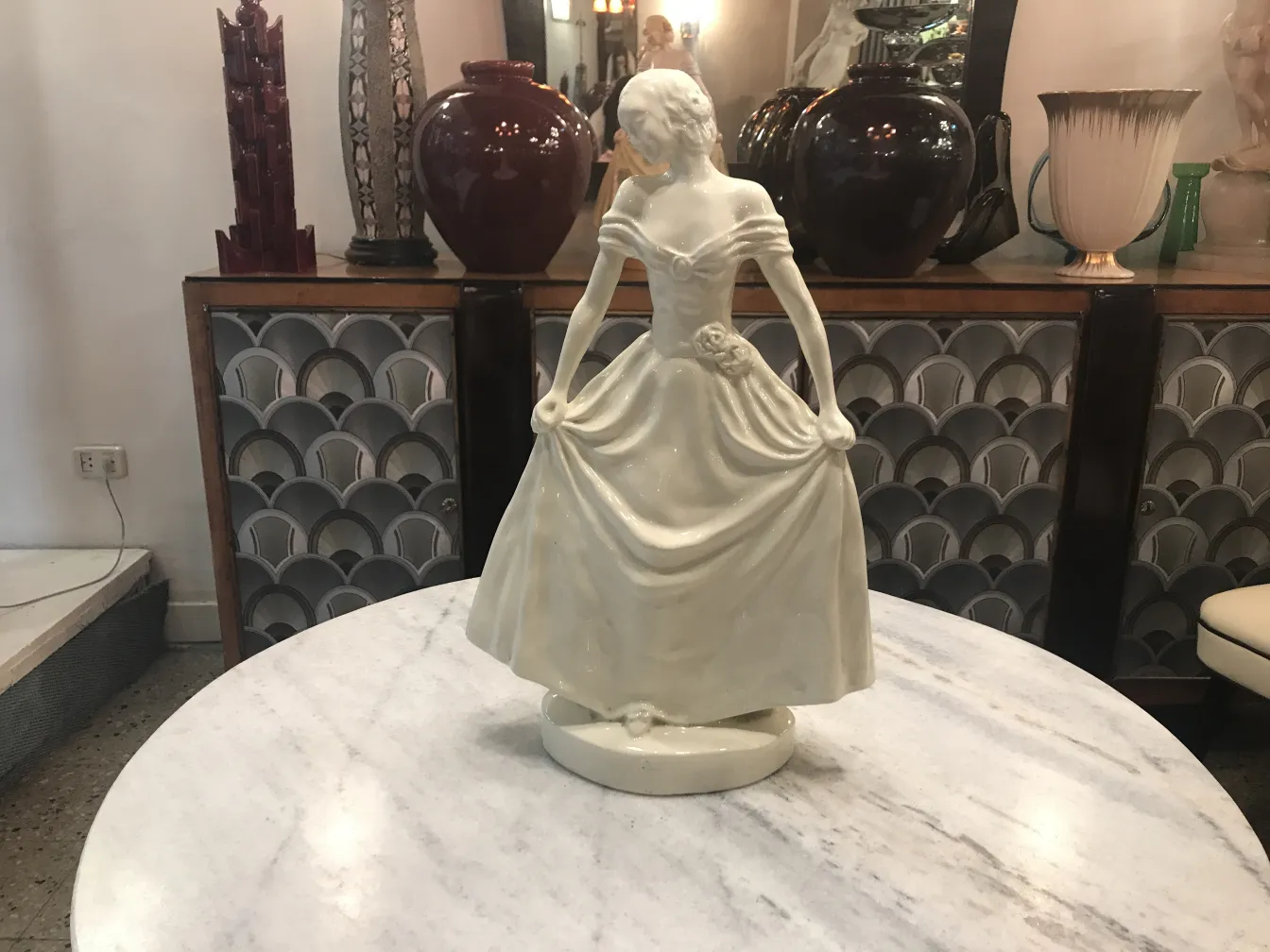 Figura decorativa in ceramica antica su un tavolo, con vasi sullo sfondo