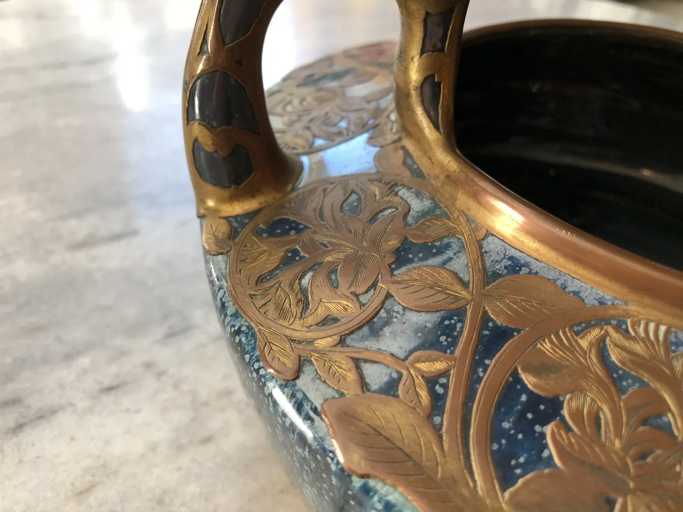 金色と青色の持ち手がついた装飾的な古陶器。