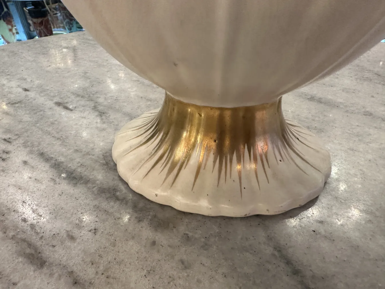 Basisdetail einer antiken Keramik mit elegantem Design und goldener Oberfläche auf hellem Hintergrund